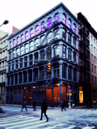A cast-iron building on a New York street corner at dusk.