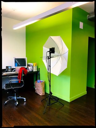 An office with a lime-green wall and a photographer’s umbrella light.